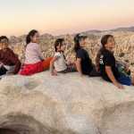 kids sitting on top of a rock