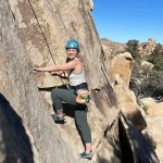 A woman who has started climbing a cliff.
